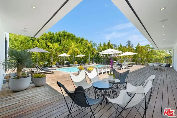 a view of a patio with table and chairs under an umbrella with a barbeque