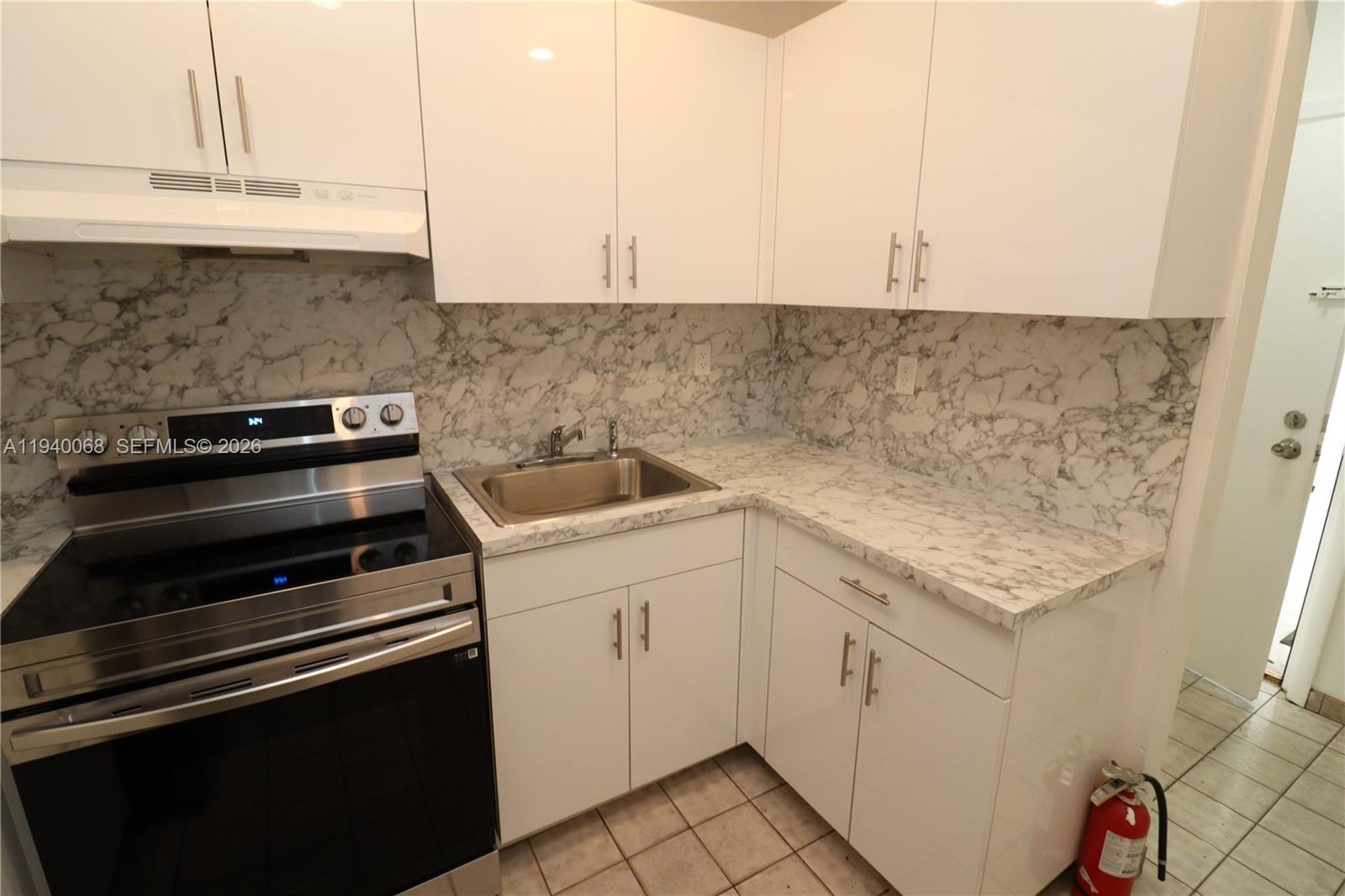 1348 Southwest 2nd Street, Unit 8 Miami, FL 33135 - Photo 2 of 37 a kitchen with granite countertop white cabinets and white appliances