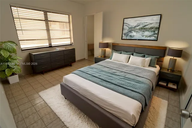 a spacious bedroom with a bed a couch and a potted plant