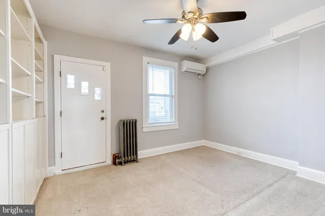 an empty room with chandelier fan and windows