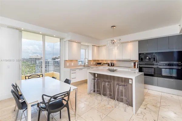 a kitchen with a stove a sink a kitchen island with chairs and wooden cabinets