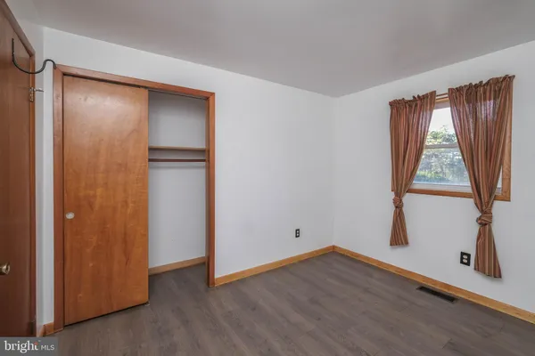 a view of an empty room with wooden floor and closet
