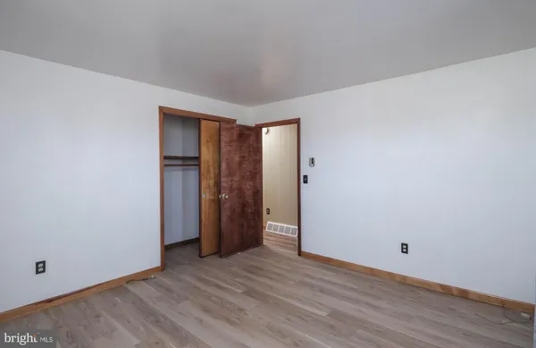 a view of an empty room with wooden floor and closet