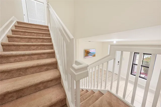 a view of staircase with lots of frames on wall and a large window