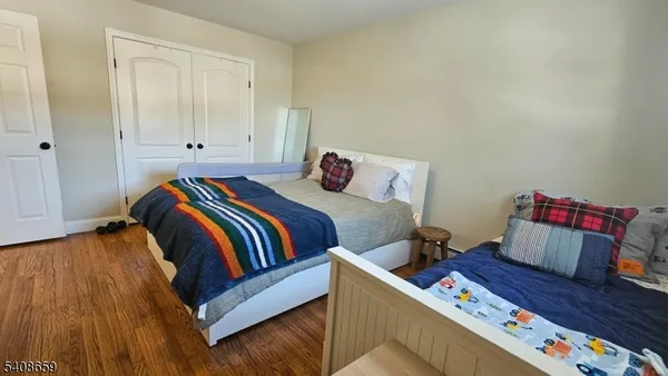 a bedroom with two beds and wooden floor