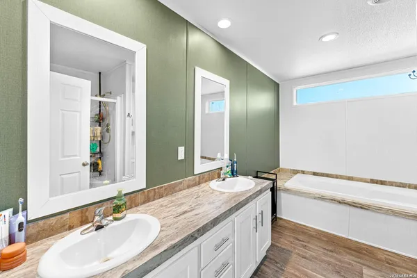 a bathroom with a granite countertop double vanity sink and a large mirror