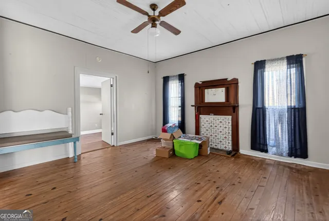 a view of an empty room with window and wooden floor