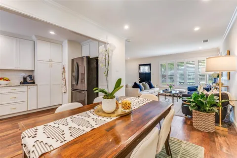 a kitchen with stainless steel appliances granite countertop a refrigerator a sink dishwasher a dining table and chairs with wooden floor