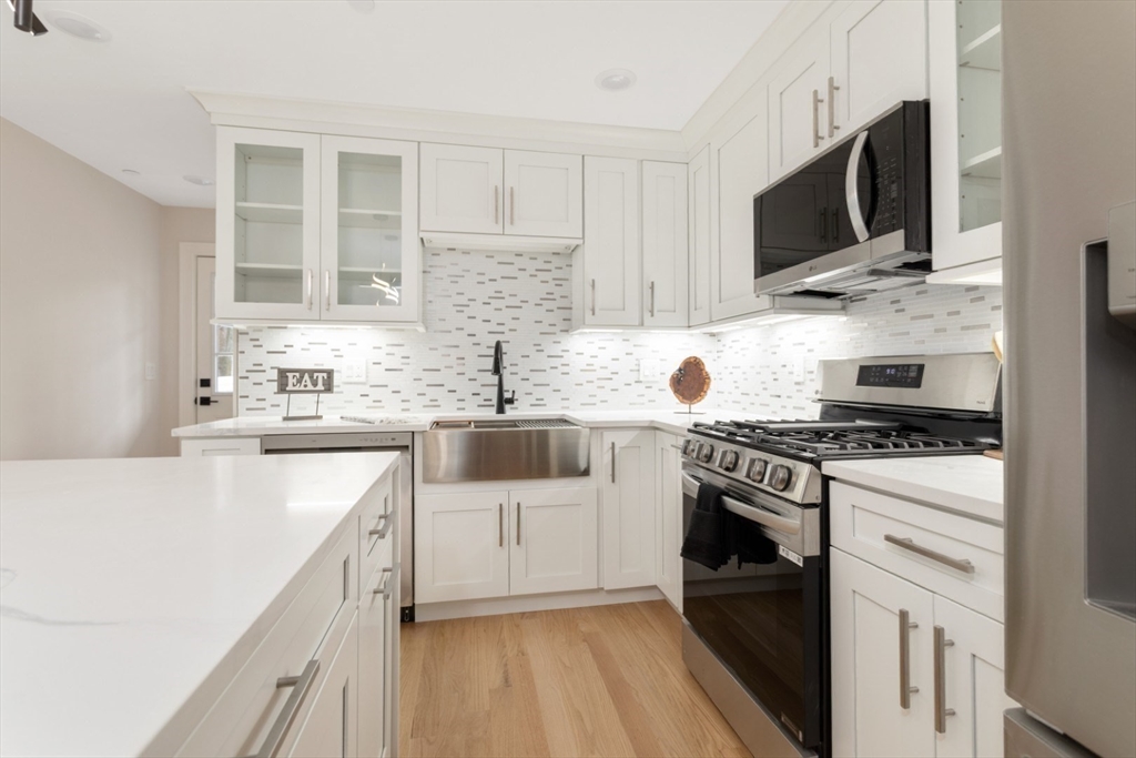 157 Boston Avenue, Unit 1 Somerville, MA 02144 - Photo 11 of 40 a kitchen with stainless steel appliances a sink stove top oven and white cabinets