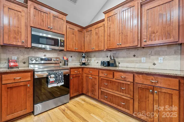 a kitchen with stainless steel appliances granite countertop a stove top oven a sink dishwasher and cabinets with wooden floor