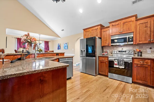 a kitchen with stainless steel appliances granite countertop a refrigerator a stove top oven a sink and dishwasher
