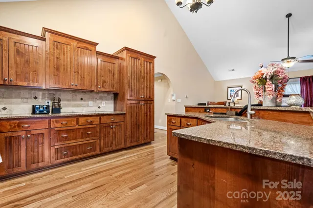 a kitchen with stainless steel appliances granite countertop a sink a stove and a wooden floors