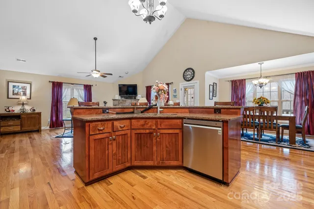 a kitchen with stainless steel appliances granite countertop a sink a stove and a wooden floors