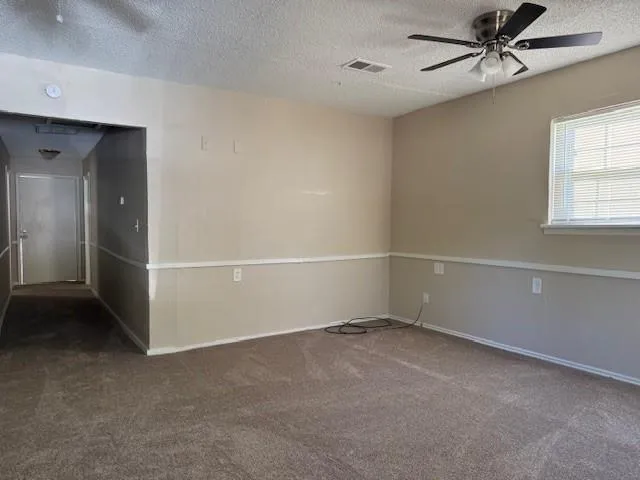an empty room with windows and fan