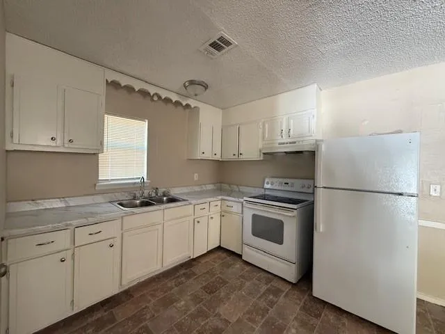 a kitchen with stainless steel appliances granite countertop white cabinets a sink a stove a refrigerator and white cabinets