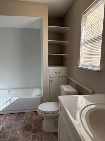 a white toilet sitting next to a bathroom sink and tub