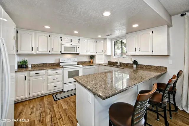 a kitchen with granite countertop kitchen island white cabinets and stainless steel appliances