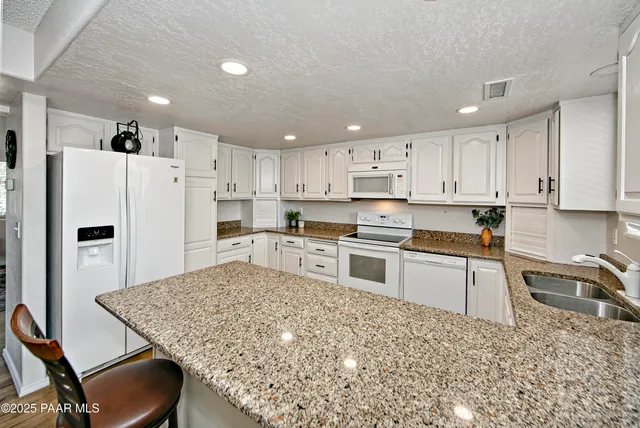 a kitchen with stainless steel appliances granite countertop a refrigerator stove microwave and sink