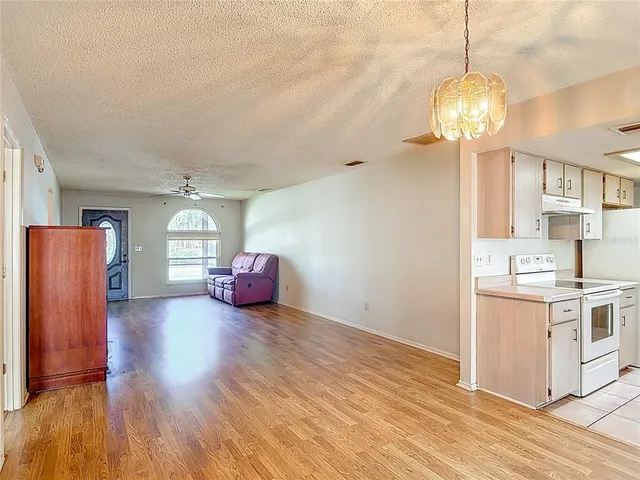a view of a kitchen and a sink wooden floor windows and a chandelier