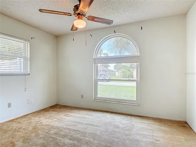 an empty room with wooden floor chandelier and fan