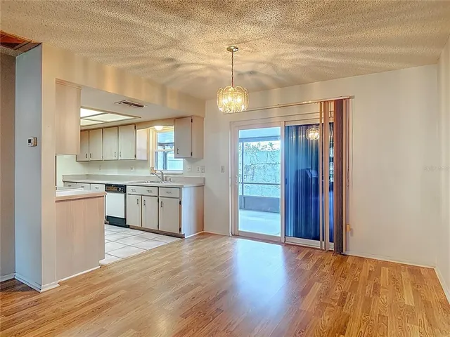 a large kitchen with granite countertop a stove a sink dishwasher and a refrigerator with wooden floor