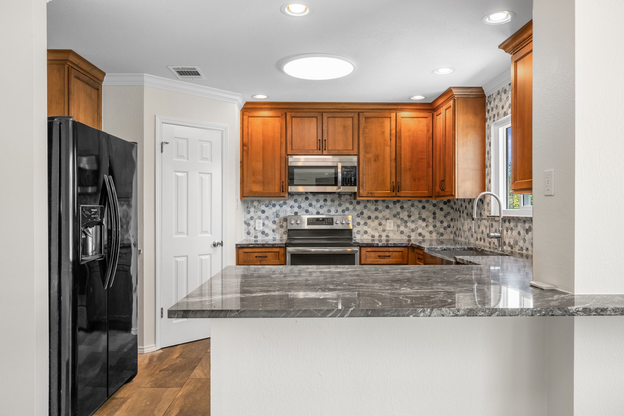 2440 Madeline Loop Cedar Park, TX 78613 - Photo 9 of 33 Kitchen with stainless steel appliances, dark stone counters, wood finish cabinetry, recessed lighting, and a peninsula