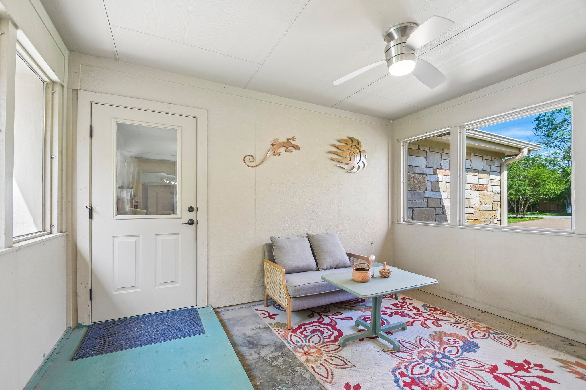 307 West 4th Street Elgin, TX 78621 - Photo 32 of 40 Enclosed patio featuring multiple windows, a ceiling fan with integrated lighting, and a paneled door with a glass insert