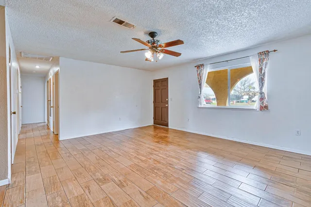 a view of an empty room with window and wooden floor