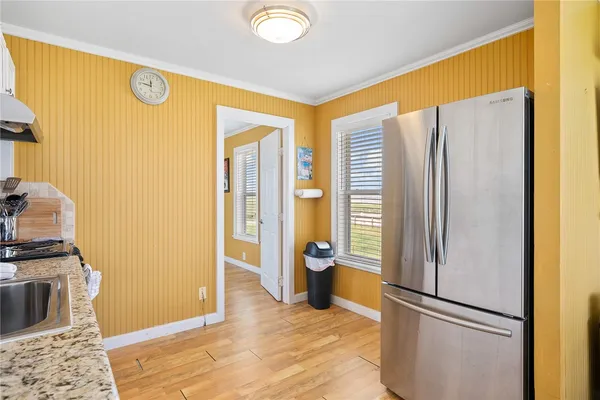 a view of a kitchen with refrigerator and wooden floor