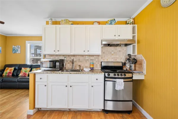 a kitchen with stainless steel appliances granite countertop a stove a sink and a microwave