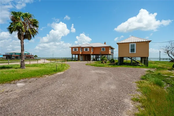 a front view of a house with a yard and palm trees