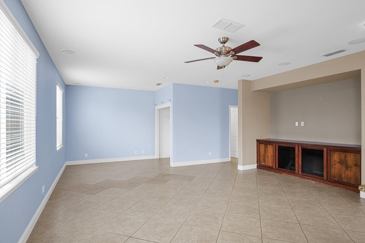 a view of an empty room with a window and a ceiling fan