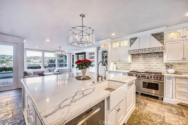 a kitchen with stainless steel appliances granite countertop a white stove top oven a sink dishwasher a dining table and chairs with wooden floor