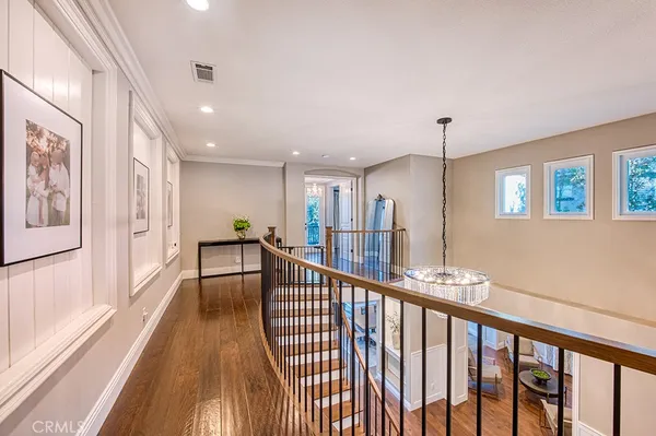 a view of a hallway with wooden floor and chandelier