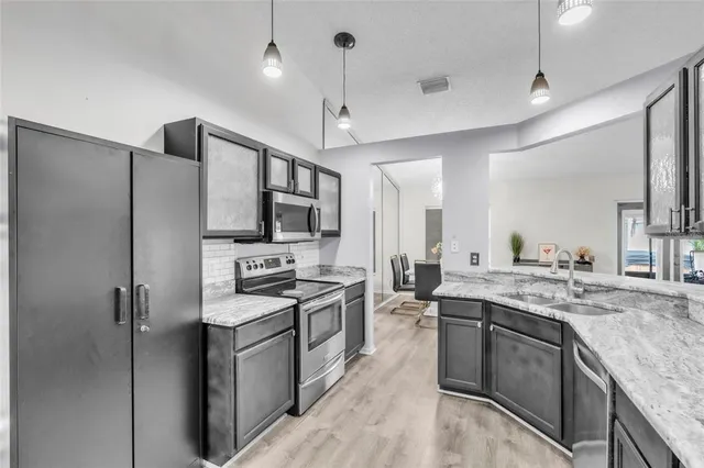 a kitchen with stainless steel appliances granite countertop a stove a sink dishwasher a refrigerator and a oven with wooden floor