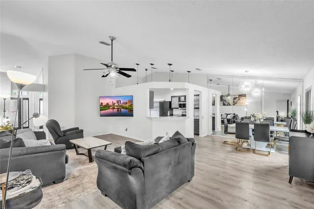 a living room with furniture kitchen view and a chandelier