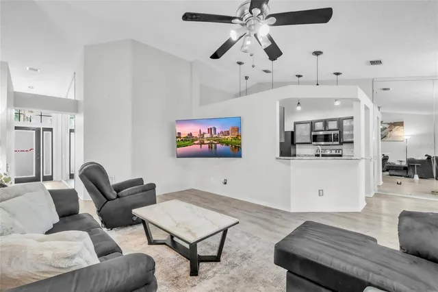 a living room with furniture kitchen view and a wooden floor
