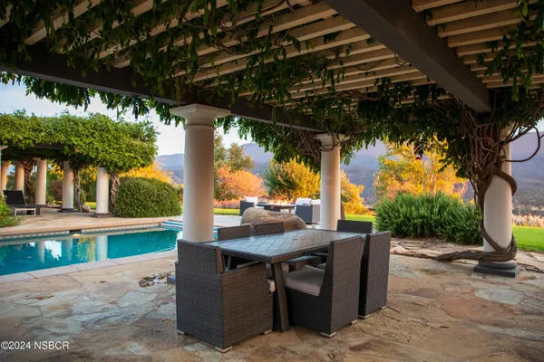 a view of a white house with a big yard and potted plants