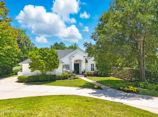 a view of a house with a big yard and large trees