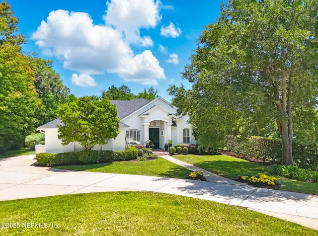 a view of a house with a big yard and large trees