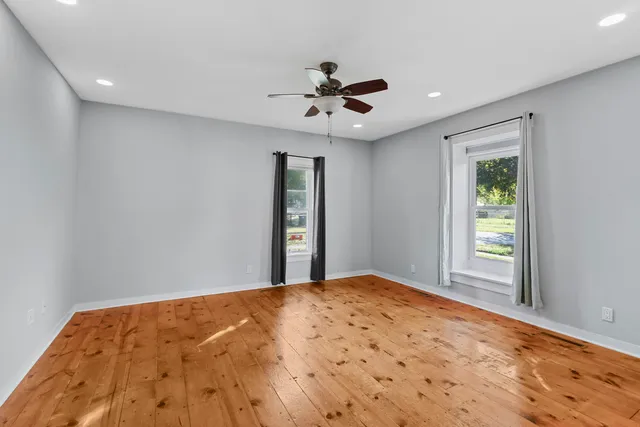 a view of a big room with windows and ceiling fan