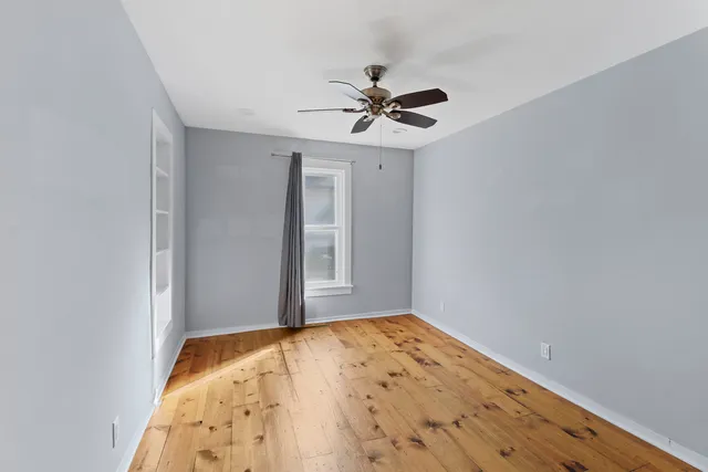 a view of a big room with wooden floor and a chandelier fan