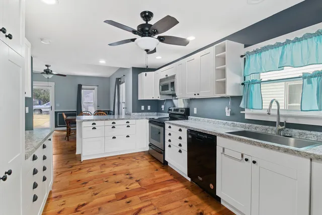 a large kitchen with kitchen island a stove a sink a chimney wooden floor and cabinets