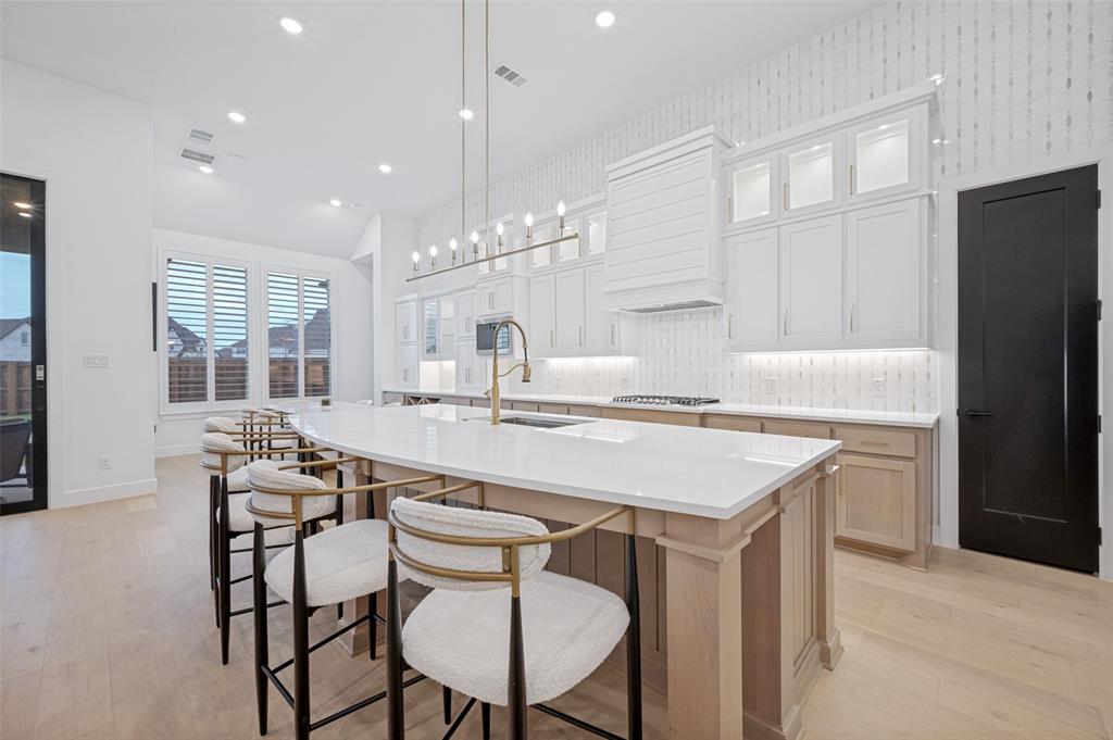 4400 Meander Way Prosper, TX 75078 - Photo 11 of 40 a kitchen with kitchen island a stove a chandelier a dining table and chairs