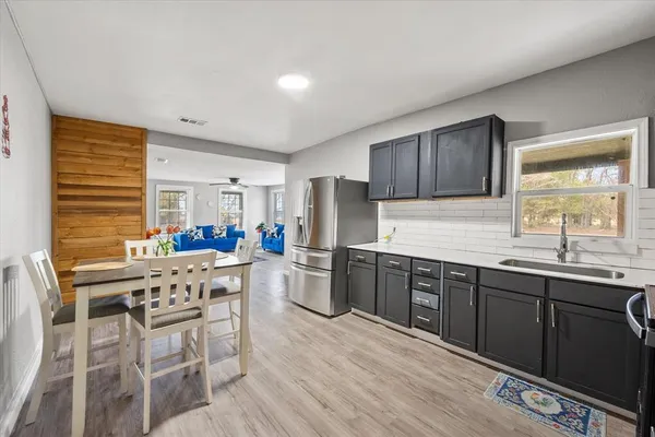 a kitchen with stainless steel appliances granite countertop a kitchen island hardwood floor sink stove dining table and chairs