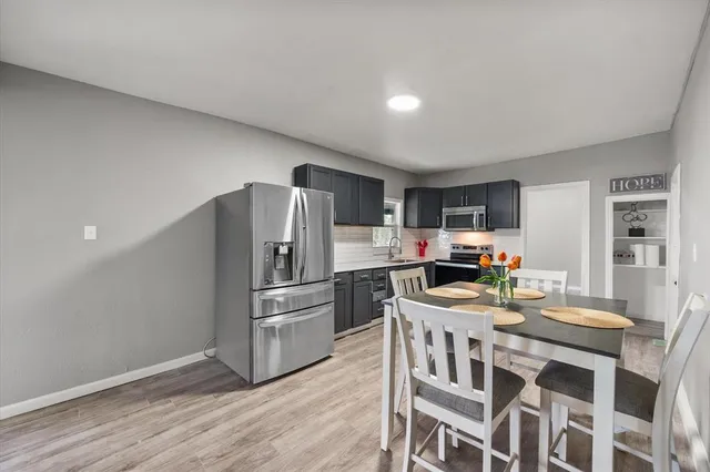 a kitchen with stainless steel appliances granite countertop a dining table chairs refrigerator and stove