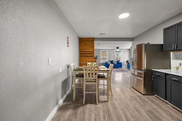 a kitchen with stainless steel appliances a dining table chairs stove and refrigerator