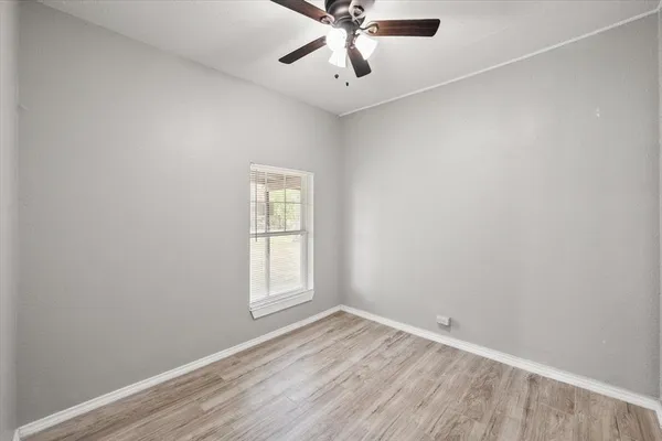 an empty room with a window and a fan