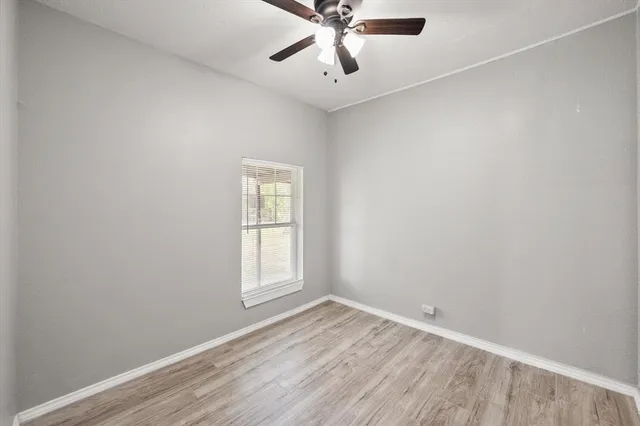 an empty room with a window and a fan