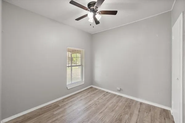 an empty room with ceiling fan and window
